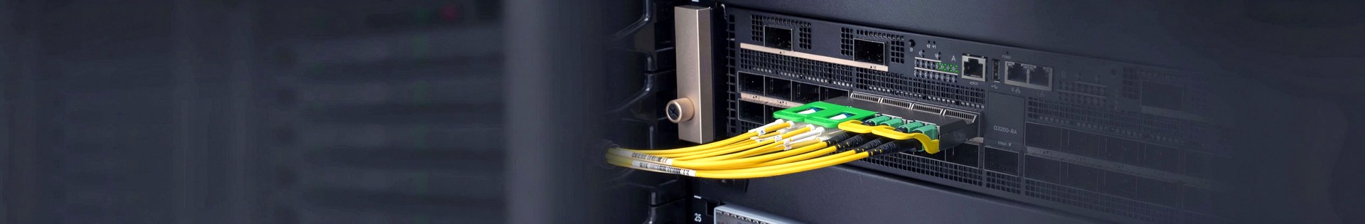 Optical transceivers and a green MPO connector plugged into a data centre switch, with a fan of yellow fibre patch cords